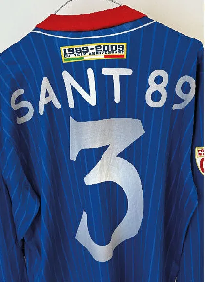 Retro di una maglia blu a righe con la scritta SANT 89, il numero 3 e la toppa 1989-2009, 20 year anniversary.