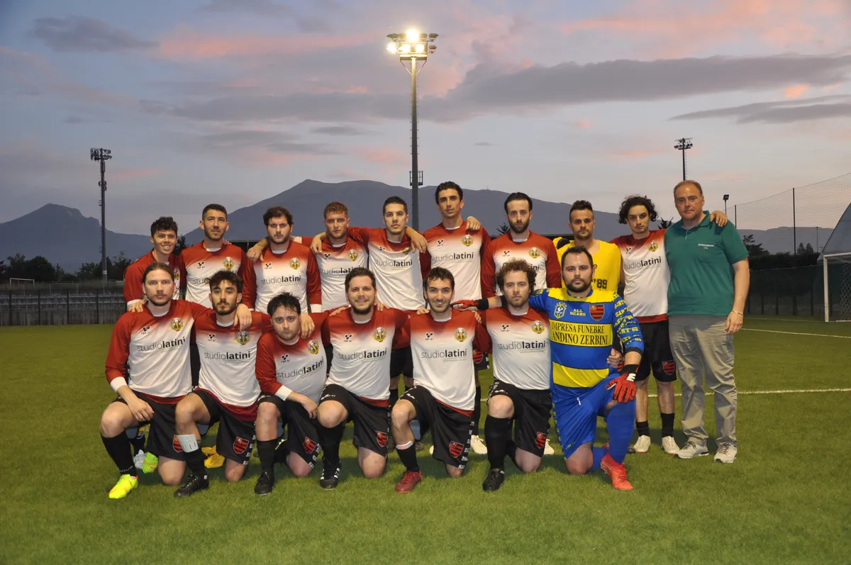 Foto di squadra al tramonto, in maglia bianca e granata, con i monti sullo sfondo.