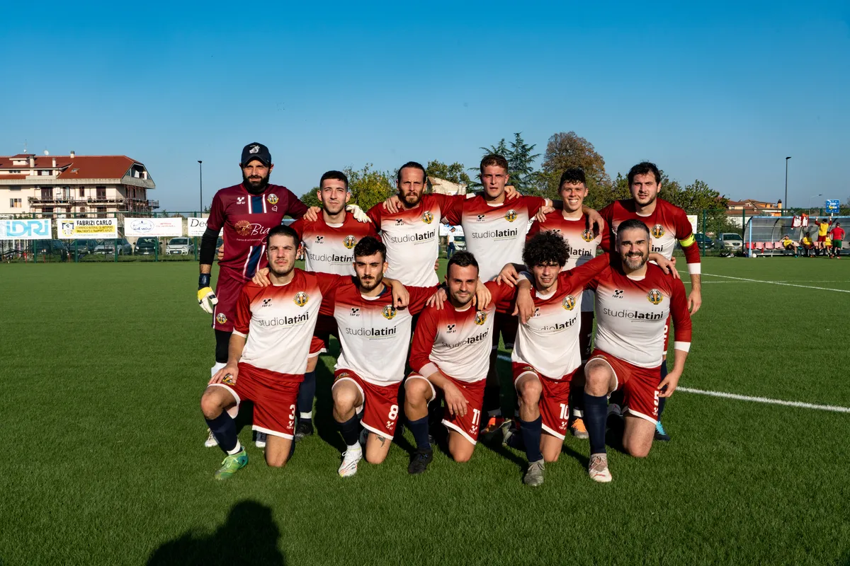 Foto di squadra in maglia bianca e granata sul campo in erba sintetica.