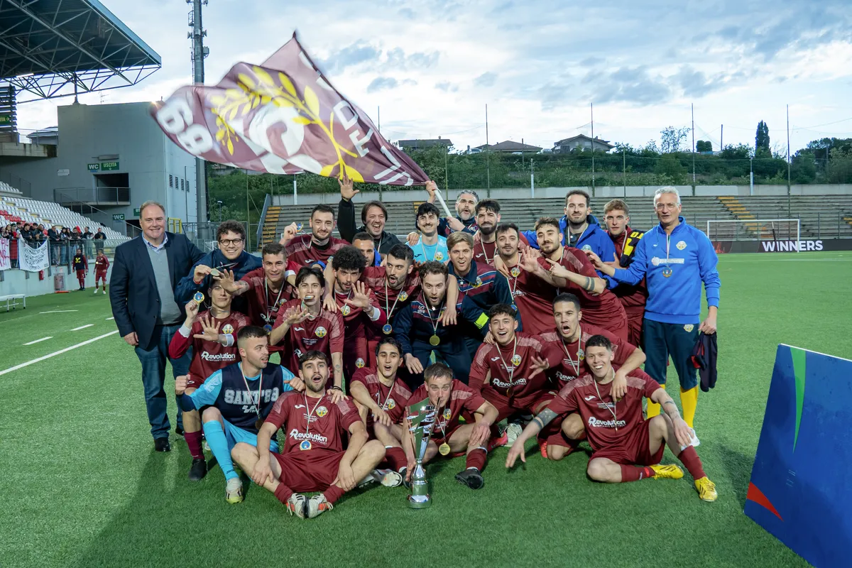 Giocatori e dirigenti festeggiano con la coppa e una bandiera granata.